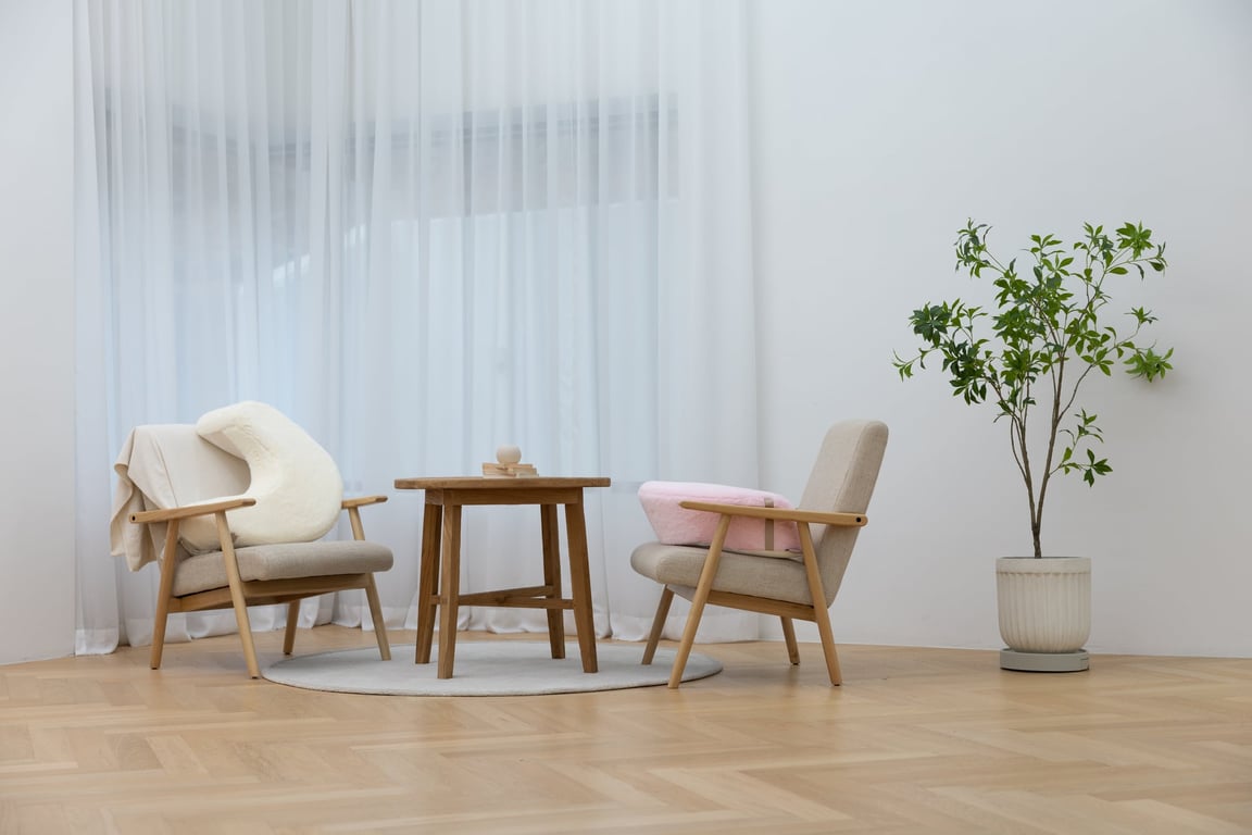 Beige and pink rabbit-fur cushions placed on wooden chairs in a minimalist studio setting