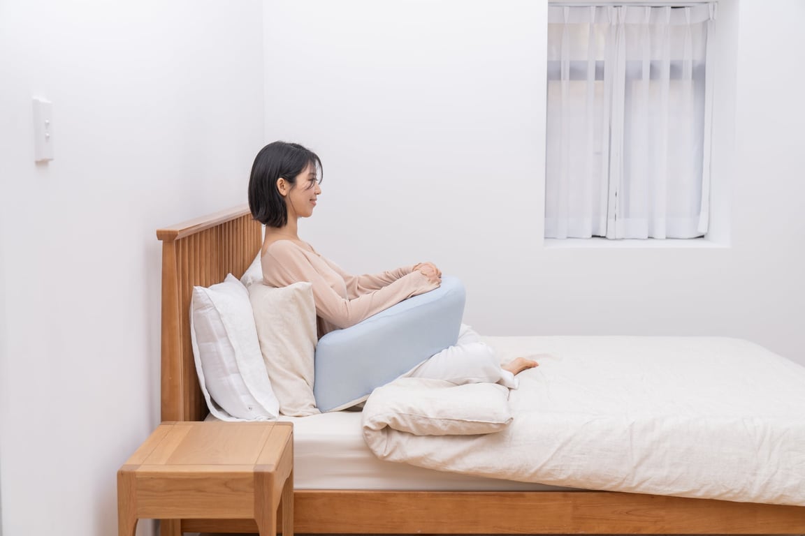앉아서 녹색 펌플렉스 레벨업쿠션에 팔을 편안하게 얹고 휴식을 취하는 여성으로, 이완을 위한 팔 지지 모습을 보여줌