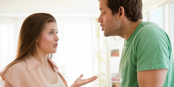 Pareja discutiendo tensa en una habitación luminosa