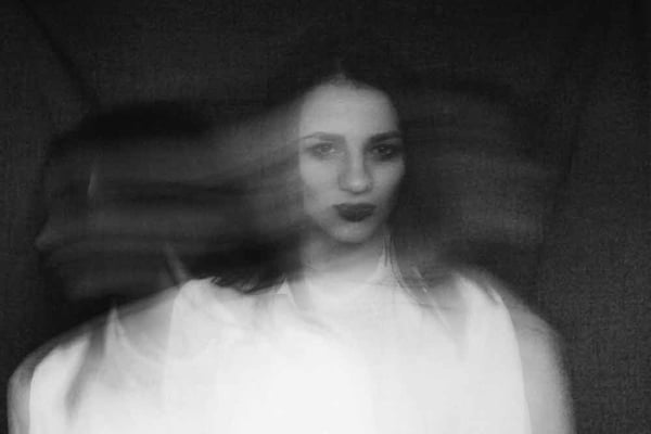 Retrato en blanco y negro de una mujer de blanco con un aura misteriosa