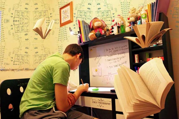 Joven estudiando en un escritorio con libros abiertos