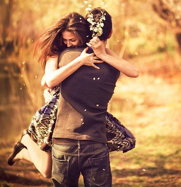 Pareja abrazándose en un campo dorado al atardecer