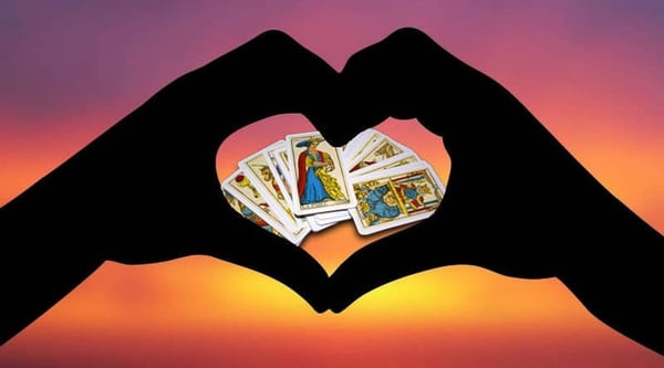 Tarot del amor: manos formando un corazón sobre las cartas