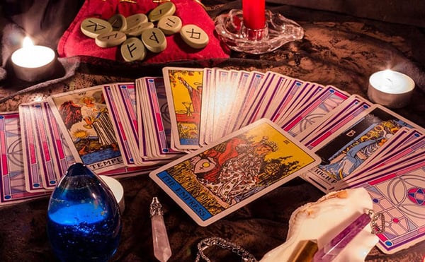 Conocer tu futuro en el amor: cartas del tarot en abanico junto a runas y una vela