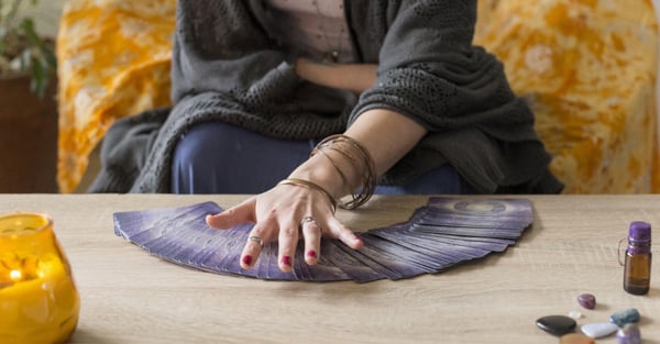 Vidente económica: manos sobre un abanico de plumas junto a una vela