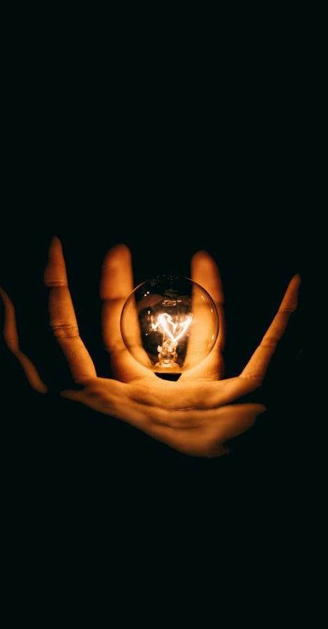 Mano de vidente sosteniendo una esfera luminosa en la oscuridad