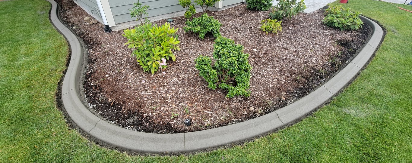 Curbing surrounding some landscaped shrubs in front of a house