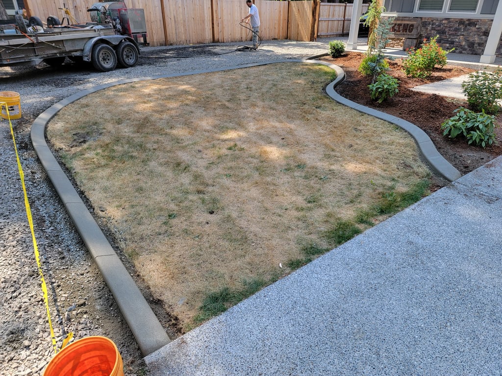 A photo of curbing surrounding a lawn with yellow grass