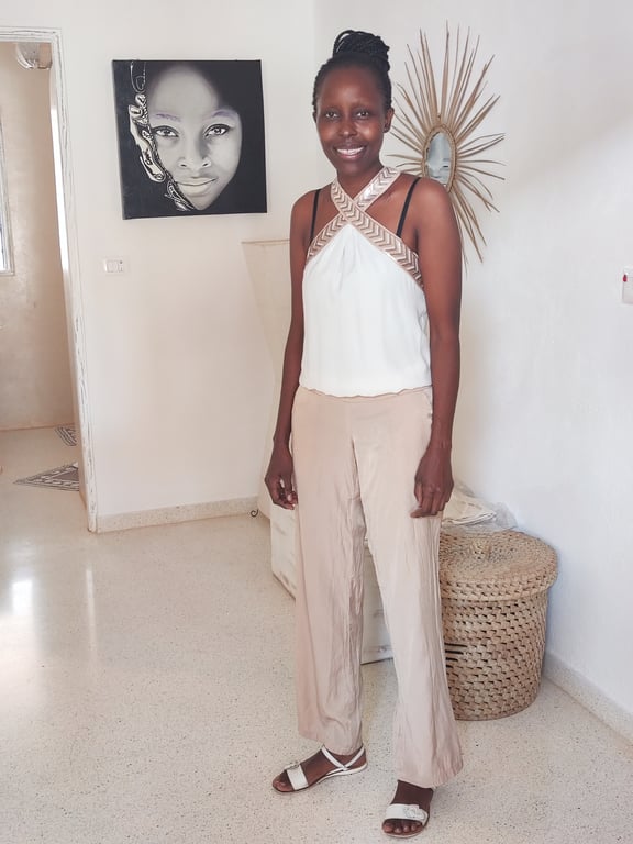 Smiling woman in a white top and beige trousers standing in a bright interior