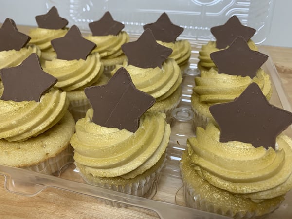 Cupcakes with gold-tinted swirled frosting and chocolate stars in a clear container, Handmade Wedding Cupcakes