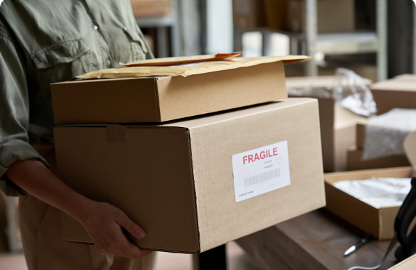 A person securely holding two cardboard boxes with 'Fragile' labels, indicating delicate contents.