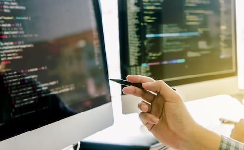 Hand with pen pointing at monitor