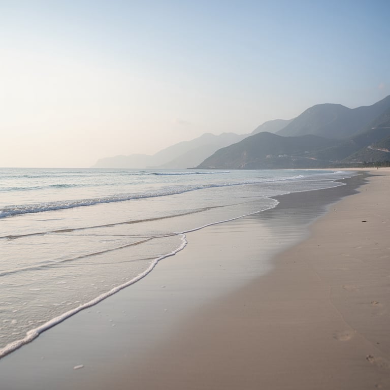 Empty stretch of My Khe Beach in Da Nang at low tide with the Hai Van Pass mountains visible in the background, Vietnam