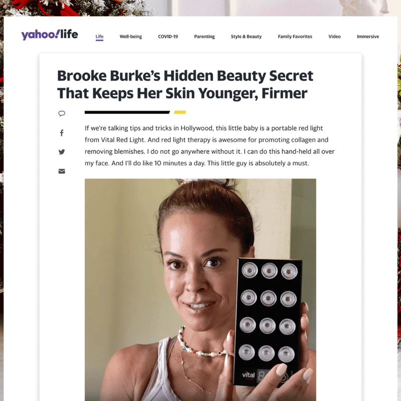 Vital Red LIght. Red Light Therapy. A woman stands indoors in front of a beige wall, smiling as she holds a small LED light therapy device with multiple bulbs. She is wearing a sleeveless top, illuminated by the gentle glow, much like a footer subtly brightening the main footer section.