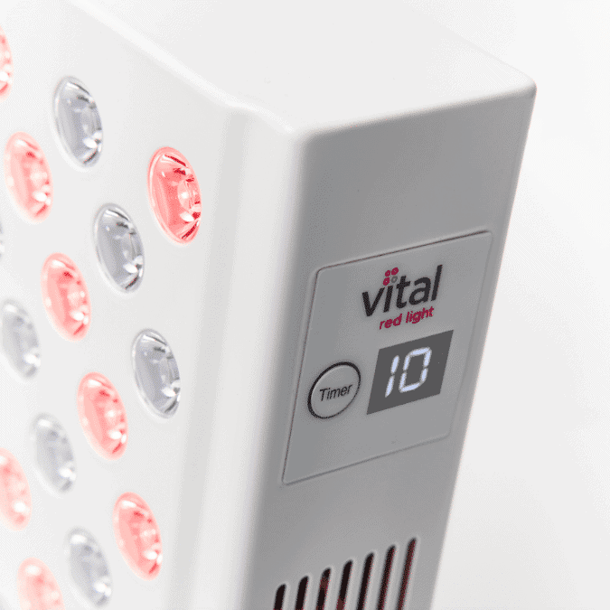 A sleek white panel with circular red and clear lights, featuring a main display indicating a timer set to 10. The brand "vital red light" is prominently printed on its surface.