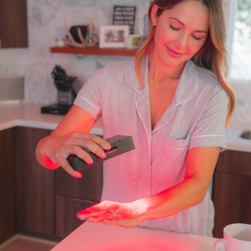 A woman using the Vital Charge red light therapy device to treat carpel tunnel