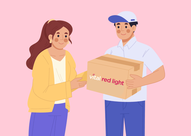 A woman in a yellow sweater receives a package labeled "vital red light" from a delivery person in a white cap and shirt.
