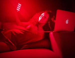 A woman using the Vital Charge red light therapy device for hormonal regulation