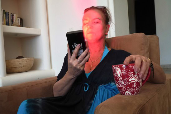 A woman using the Vital Charge red light therapy device to combat age related macular degeneration