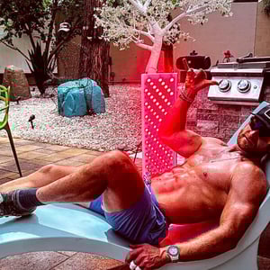 A fit man using his Vital Elite red light therapy device for muscle recovery and biohacking