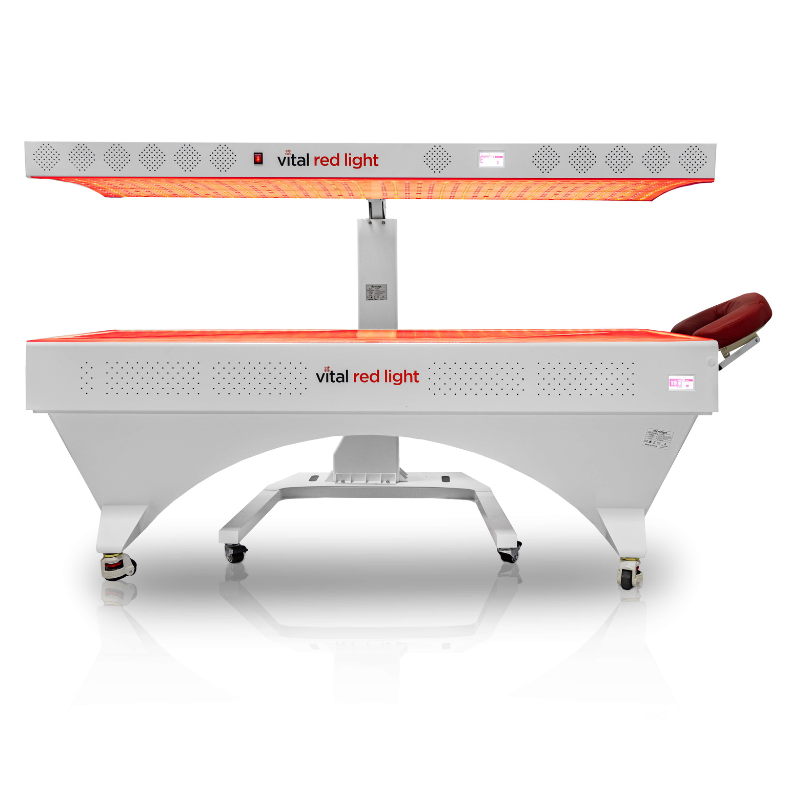 Vital Red LIght. Red Light Therapy. Horizontal red light therapy bed with an overhead light panel, labeled "vital red light," featuring a cushioned headrest and mounted on wheels.