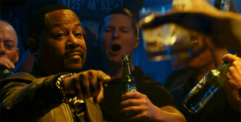 TechDogs-"A Celebratory Scene From The Movie "Bad Boys" With Will Smith And Martin Lawrence Raising Drinks And Smiling Towards Each Other."