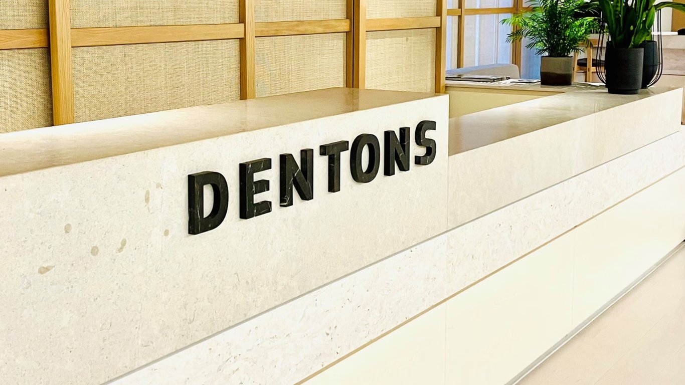 TechDogs-"An Image Of Dentons Logo On A Desk As Used In Legora's News Release"