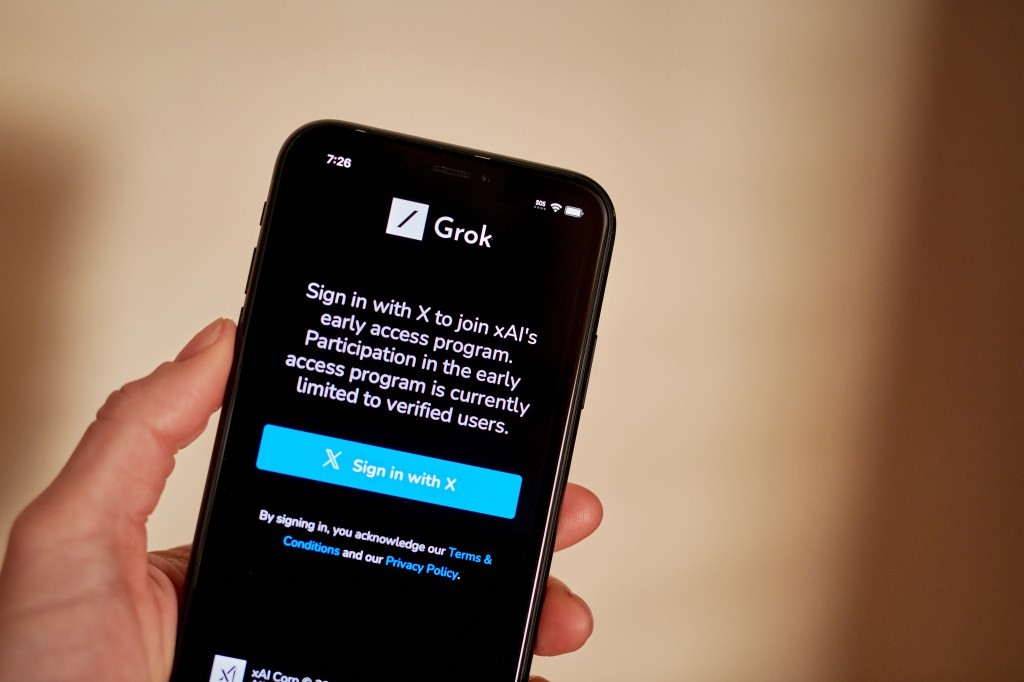 TechDogs-"What’s New With Grok?"-"Hand Holding Phone Displaying Grok iOS App Login Screen for xAI's Early Access Program Limited to Verified Users"