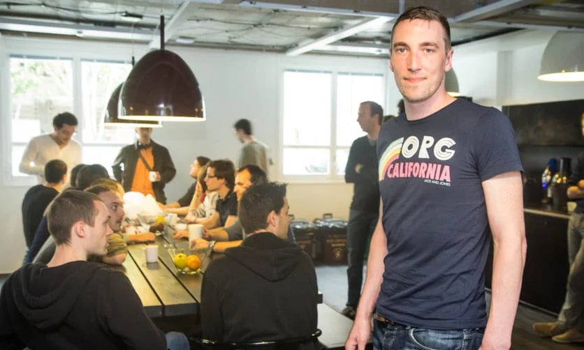 TechDogs-"Deezer’s Chief Innovation Officer Aurelien Herault Standing In Office With Team In Background"
