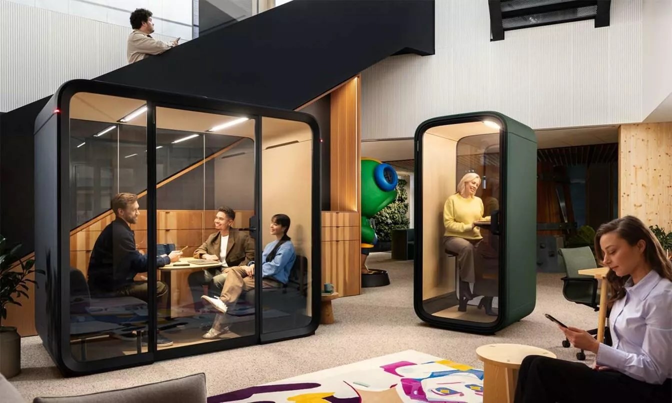 TechDogs-"Smart Furniture"-"Image Of Contemporary Office Space With Soundproof Meeting Pods, A Lounge Area, And Employees Working In Flexible Seating Zones"