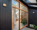 Preview of Ainslie Remodel and Addition - Image 8: pivot door, siding, wood, glass, vertical slats, skylights, landscaping, natural light, modern design, exterior lighting, stone flooring.