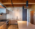 Preview of Vashon Island Cabin - Image 9: kitchen, wood cabinetry, modern, minimalist, stainless steel, wood ceiling, pendant lighting, integrated appliances, concrete floor, open shelving, recessed lighting, island counter, contemporary design, natural materials, clean lines, metal finishes.
