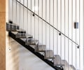 Preview of Vashon Island Cabin - Image 17: stair, modern, minimalist, industrial, structure steel, wood beams, black steel, concrete floor, wooden ceiling, metal railing, open riser staircase, contemporary design, interior design, indoor staircase, architectural feature, sleek design, lighting fixtures, wall-mounted railings.