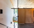 Preview of Vashon Island Cabin - Image 20: stair, wood ceiling, black steel, minimalist, modern, glass partition, sliding door, concrete floor, natural light, wall sconces, railing, urban, contemporary.