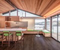 Preview of KITCHEN CONNECTED - Image 0: kitchen, wood ceiling, wood cabinetry, bar seating, pendant lighting, modern design, open space, large windows, waterfront view, sliding glass doors, recessed lighting, built-in seating, dark wood floor, contemporary architecture, minimalist, indoor-outdoor connection, natural light.
