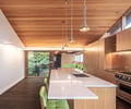 Preview of KITCHEN CONNECTED - Image 2: kitchen, wood ceiling, pendant lighting, large windows, natural light, modern design, island countertop, built-in appliances, wood cabinets, stainless steel, open layout, contemporary style, minimalist decor, white countertops, indoor-outdoor connection.