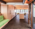 Preview of KITCHEN CONNECTED - Image 6: kitchen, wood paneling, large windows, natural lighting, green upholstery, wooden beams, built-in seating, open concept, modern design, dark wood floor, island counter, recessed lighting, minimalist style.