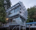 Preview of Lagerberg Mooring - Image 3: modern house, stilt house, elevated structure, metal railing, large windows, glass facade, exterior lighting, metal staircase, balcony, waterfront, contemporary design, grid, steel structure, metal cladding.