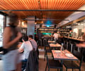 Preview of Mamnoon Street - Image 1: Human, Person, Bar Counter, Wood, Steel, Glass, Window, Dining Table, Restaurant, Bar.