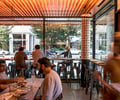 Preview of Mamnoon Street - Image 9: People, Cafe, Chair, Slide, Steel, Wood, Window, Glass, Dining Table, Restaurant, Storefront, Concrete.