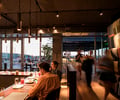Preview of Mbar - Image 11: Human, Person, Restaurant, Glass, Window, Concrete, Steel, Bar, Dining Table, Wood, Rooftop, Outdoor, Structure Steel, Pergola.