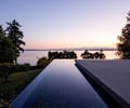 Preview of Northwest Reflections - Image 0: infinity pool, concrete deck, water feature, modern design, minimalist, outdoor space, landscape integration, horizon view, glass edge, serene setting, residential architecture, evening light, natural materials.