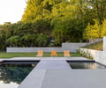 Preview of Northwest Reflections - Image 5: concrete wall, pool, outdoor seating, garden, landscape design, concrete floor, modern design, greenery, trees, minimalistic, patio, outdoor living, relaxation area, natural setting, hardscape, lounge chairs, retaining wall, flat surface, paved area, water feature, contemporary architecture.