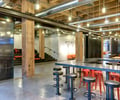 Preview of Payscale - Image 0: industrial, modern, structure wood, structure steel, black steel, concrete floor, open ceiling, exposed ductwork, pendant lights, communal table, bar stools, wooden beams, metallic surfaces, interior design, urban, exposed pipes, red accents, multi-level seating, concrete wall, workshop style, gathering space, informal seating, minimalistic lighting, exposed ceiling, event space, historic.