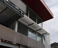 Preview of Shapiro Residence - Image 1: Potted Plant, Porch, Building, Canopy, Apartment Building, City, High Rise, Town, Urban, Exterior glass, Structure steel, sliding door, Cantilever, Window, sun screen, grating, color, deck.