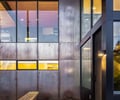 Preview of Sun Valley Fireweed - Image 8: glass facade, large windows, wood ceiling, concrete wall, concrete floor, exterior lighting, bench, outdoor seating, metal frame, modern design, minimalist, natural light, corten, sustainable materials, architectural glazing.