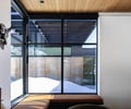 Preview of Sun Valley Fireweed - Image 22: glass wall, large window, natural light, cantilever, modern architecture, wooden ceiling, concrete wall, minimalist design, interior design, metal frame, outdoor view, bench seating, decorative wall art.