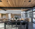 Preview of Sun Valley Fireweed - Image 25: kitchen, open plan, modern design, wood ceiling, black chairs, pendant lighting, glass walls, sliding doors, natural light, concrete floor, island counter, minimalist, interior design, dining area, sleek lines, neutral tones, indoor plants, bar stools, cabinetry, countertops, contemporary style.