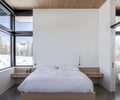 Preview of Sun Valley Fireweed - Image 31: bedroom, large windows, natural light, wooden ceiling, minimalist design, neutral colors, sliding door, modern architecture, concrete floor, snow view, built-in furniture, contemporary style, reading lights.