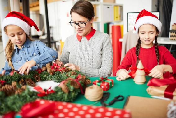 professora e alunas felizes decorando a guirlanda de natal 1 1